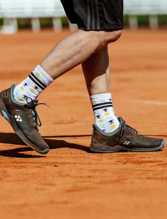 Mann spielt Tennis auf Sandplatz